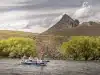 Two fisherman and a fishing guide fishing from a boat on the Chimehuin river in front of Tipiliuke mountain in Patagonia