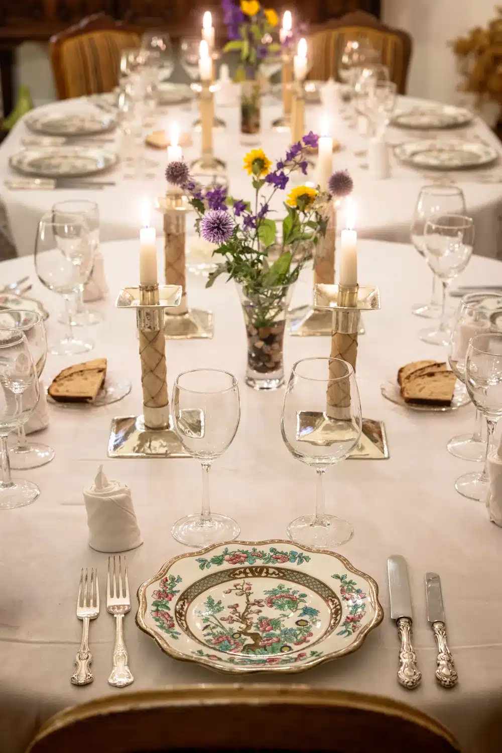 place setting with candles, silver service, flowers and decorative china at Arroyo Verde lodge Patagonia