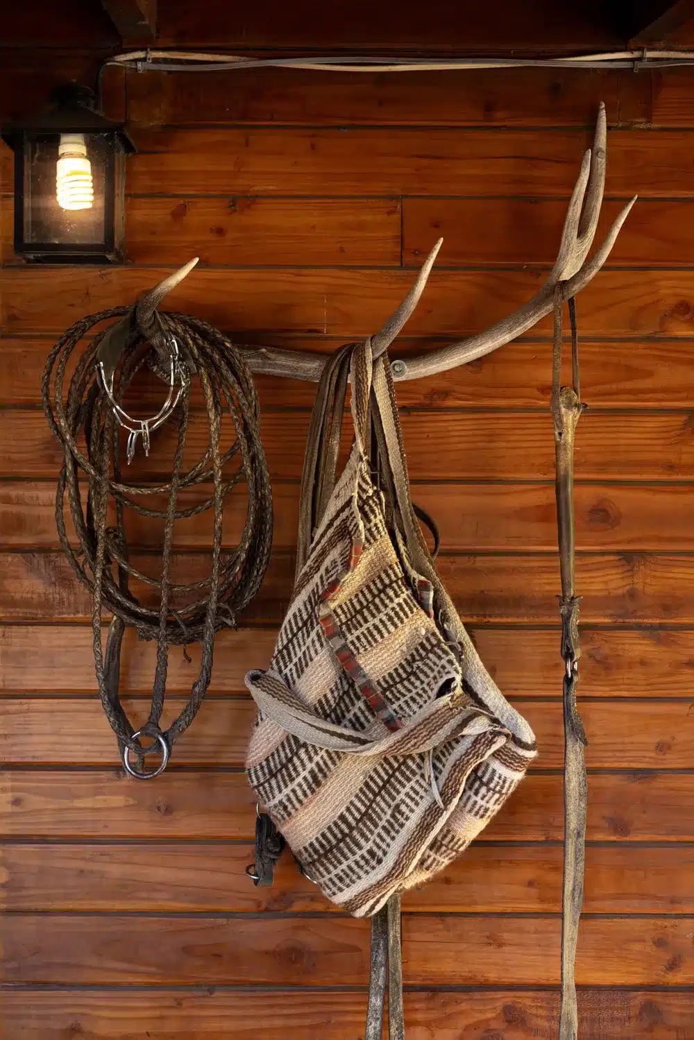 knitted saddlebags, a rebenque and a lasso hanging from an antler on a wall at Arroyo Verde lodge Patagonia